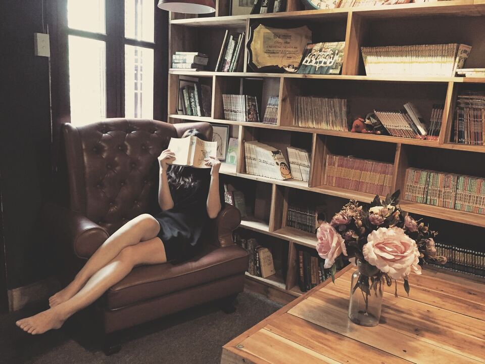 A reader settled into a leather armchair beside a bookshelf